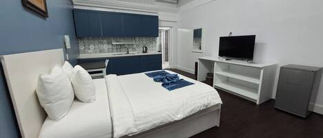 Une chambre avec un lit, une télévision, une petite kitchenette et une salle de bain.