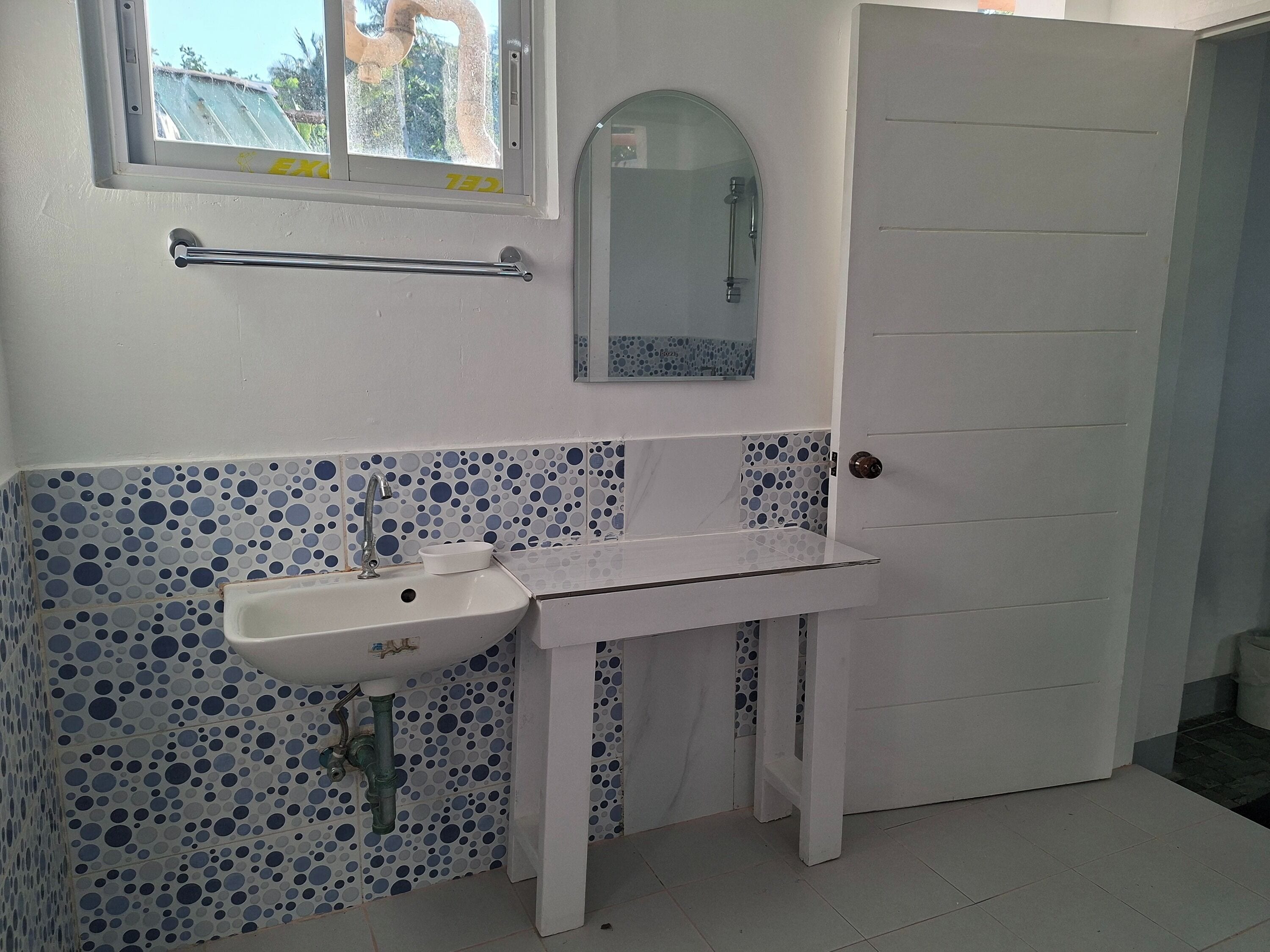 Un baño con un lavamanos blanco, un espejo y una ventana.