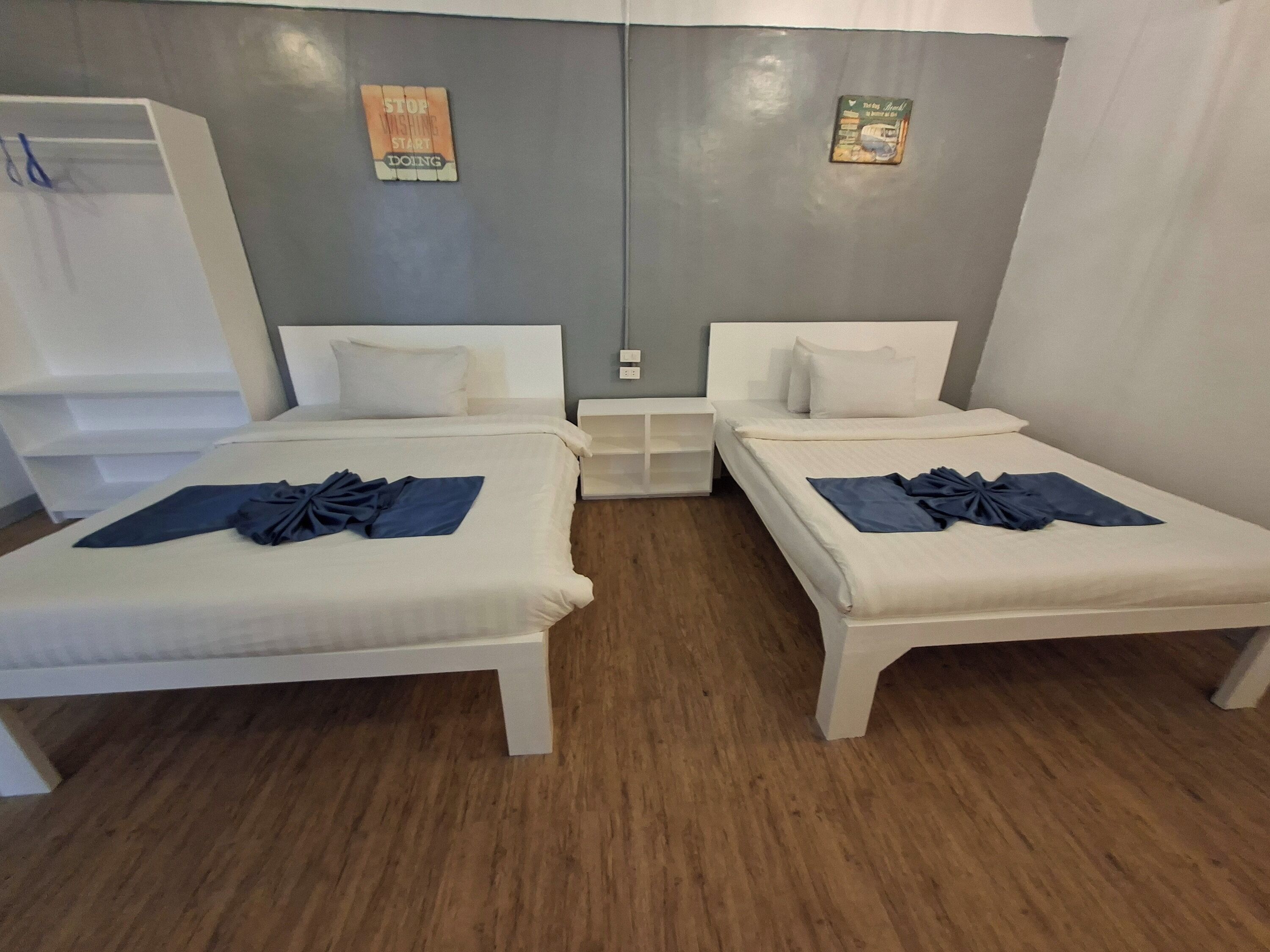 Une chambre d’hôtel avec deux lits, une table de chevet, une armoire et un mur orné d’affiches motivantes.