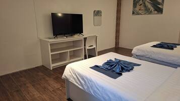 Habitación de hotel con dos camas, un televisor sobre un mueble, una silla y un cuadro en la pared.