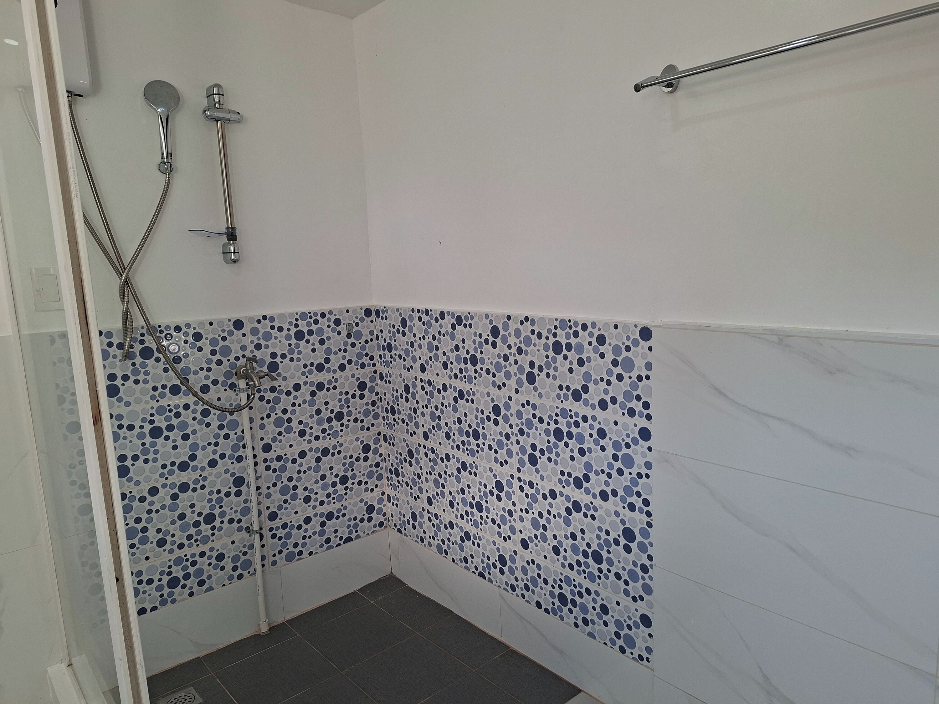 A shower with a tiled wall, a showerhead, and a handheld shower attachment.