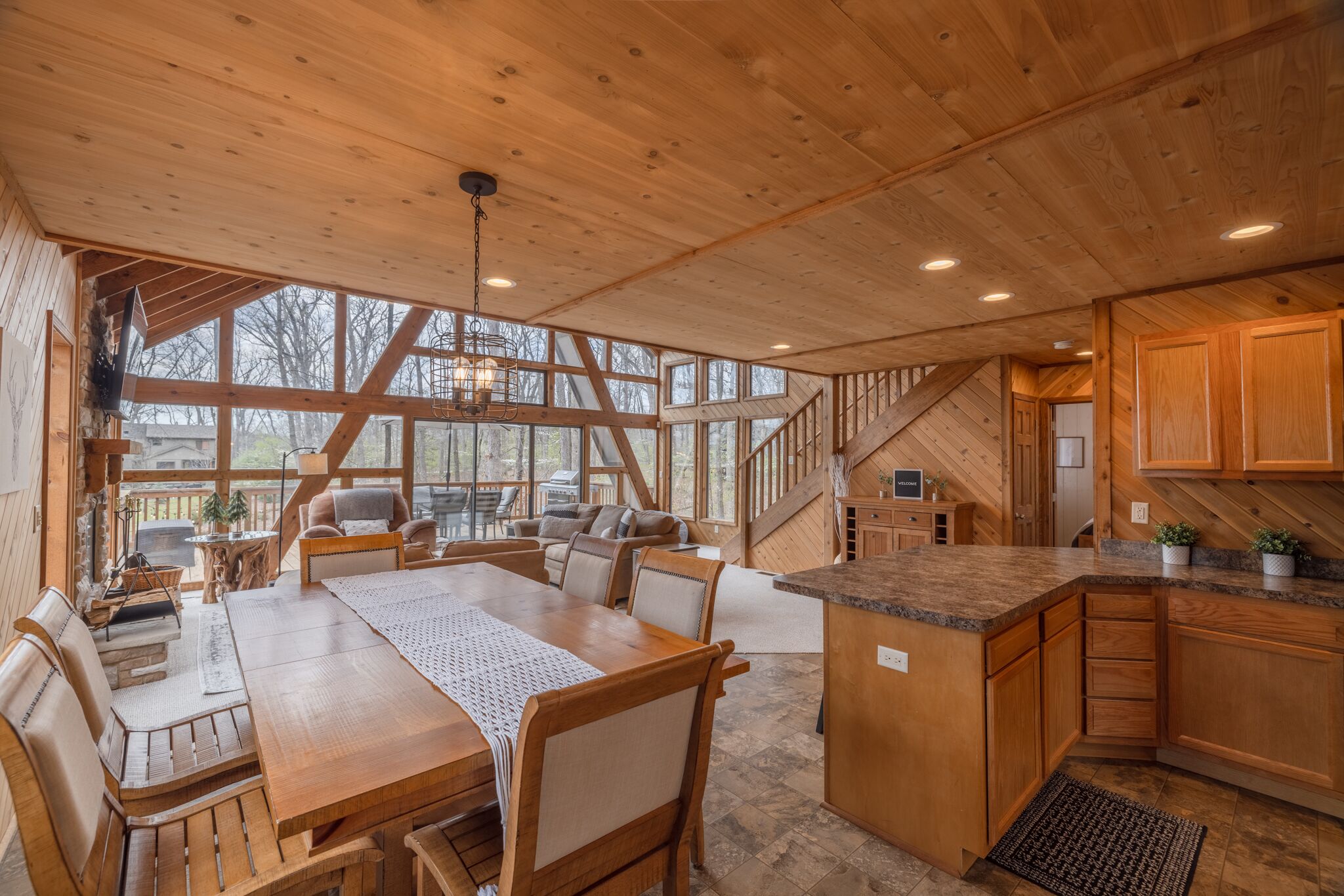A spacious wooden cabin with a dining area, kitchen, and a staircase leading to an upper level.