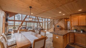 A spacious wooden cabin with a dining area, kitchen, and a staircase leading to an upper level.