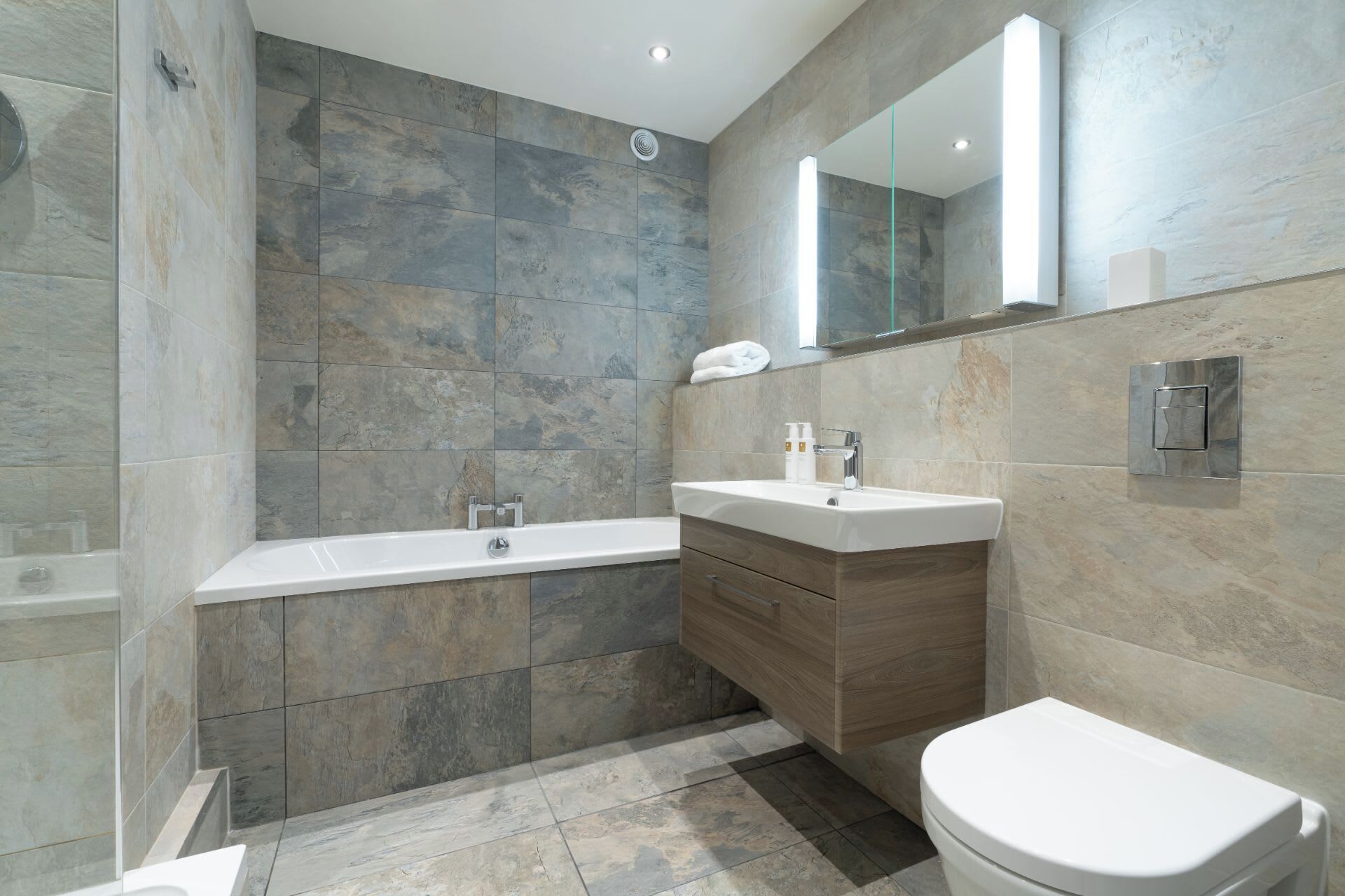 A modern bathroom with a bathtub, a sink, and a toilet.