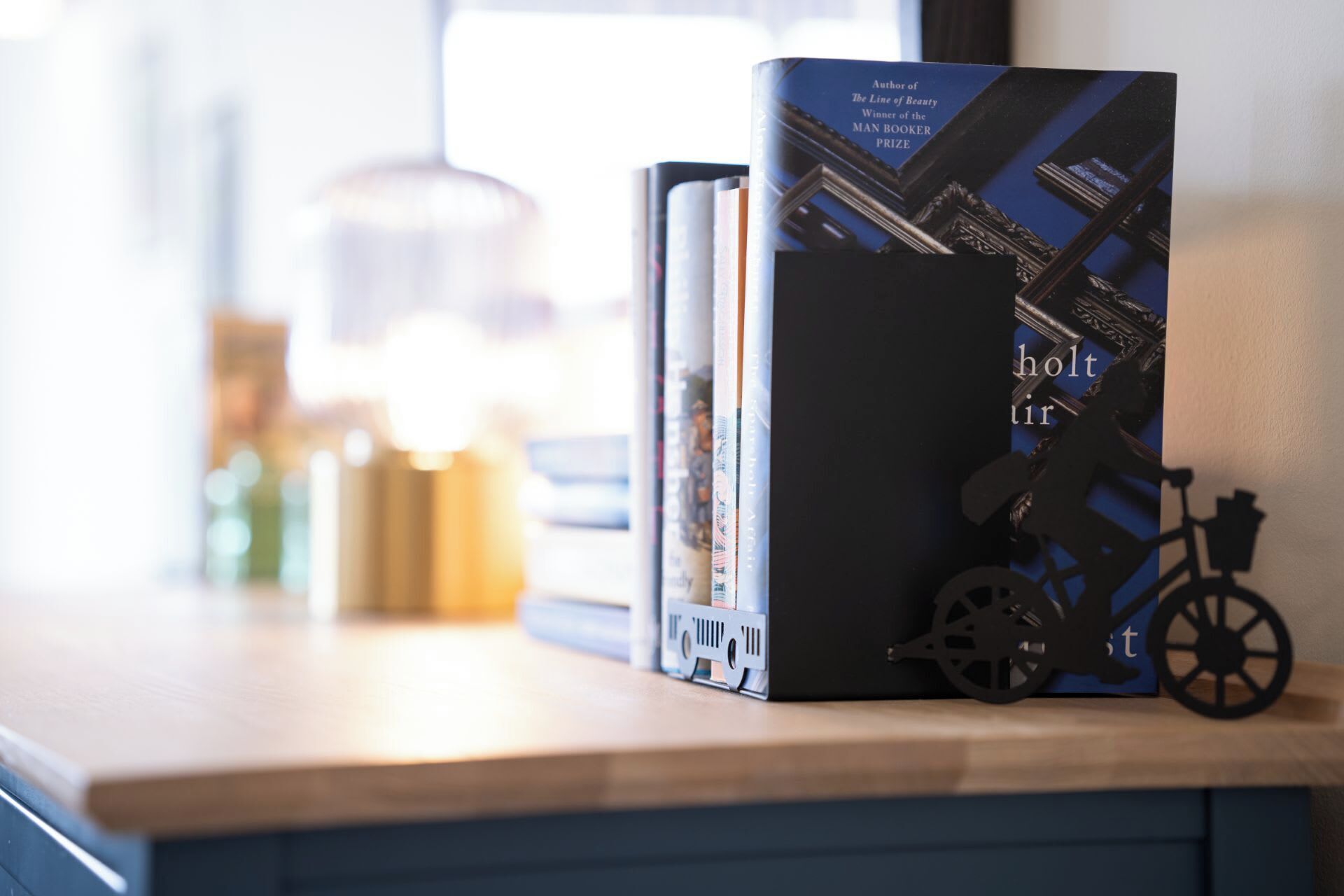 Un livre intitulé « holt » est posé sur une étagère, à côté d’autres livres. On aperçoit également un vélo et une lampe en arrière-plan.
