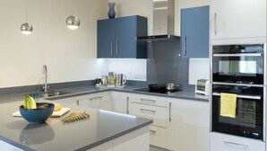 Una cucina moderna con isola centrale, elettrodomestici integrati e illuminazione a sospensione.