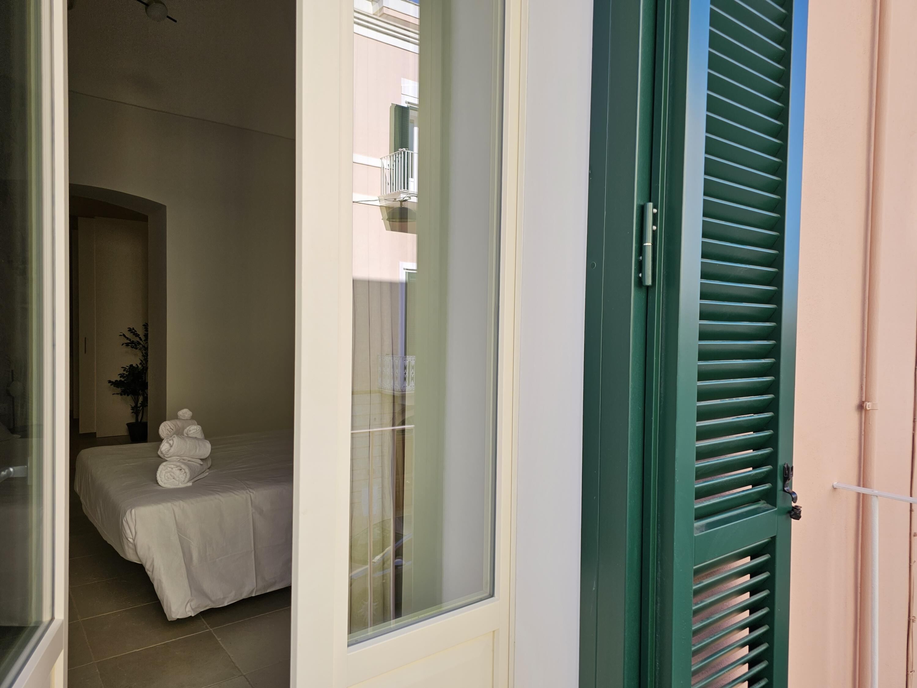 Un dormitorio con cama, una planta en maceta y una ventana con persianas.