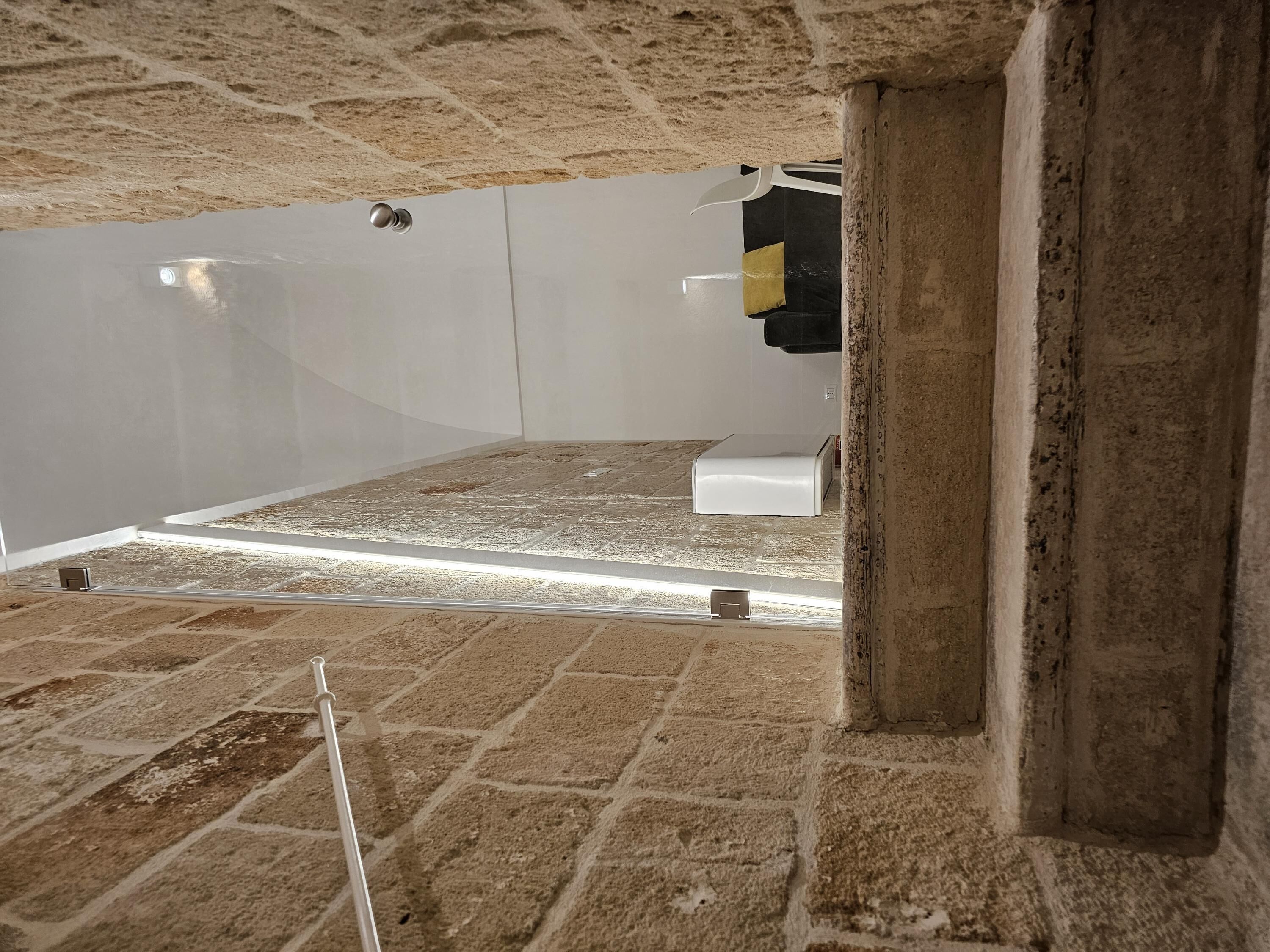 A room with exposed brick walls, a white door, and a white air conditioning unit.