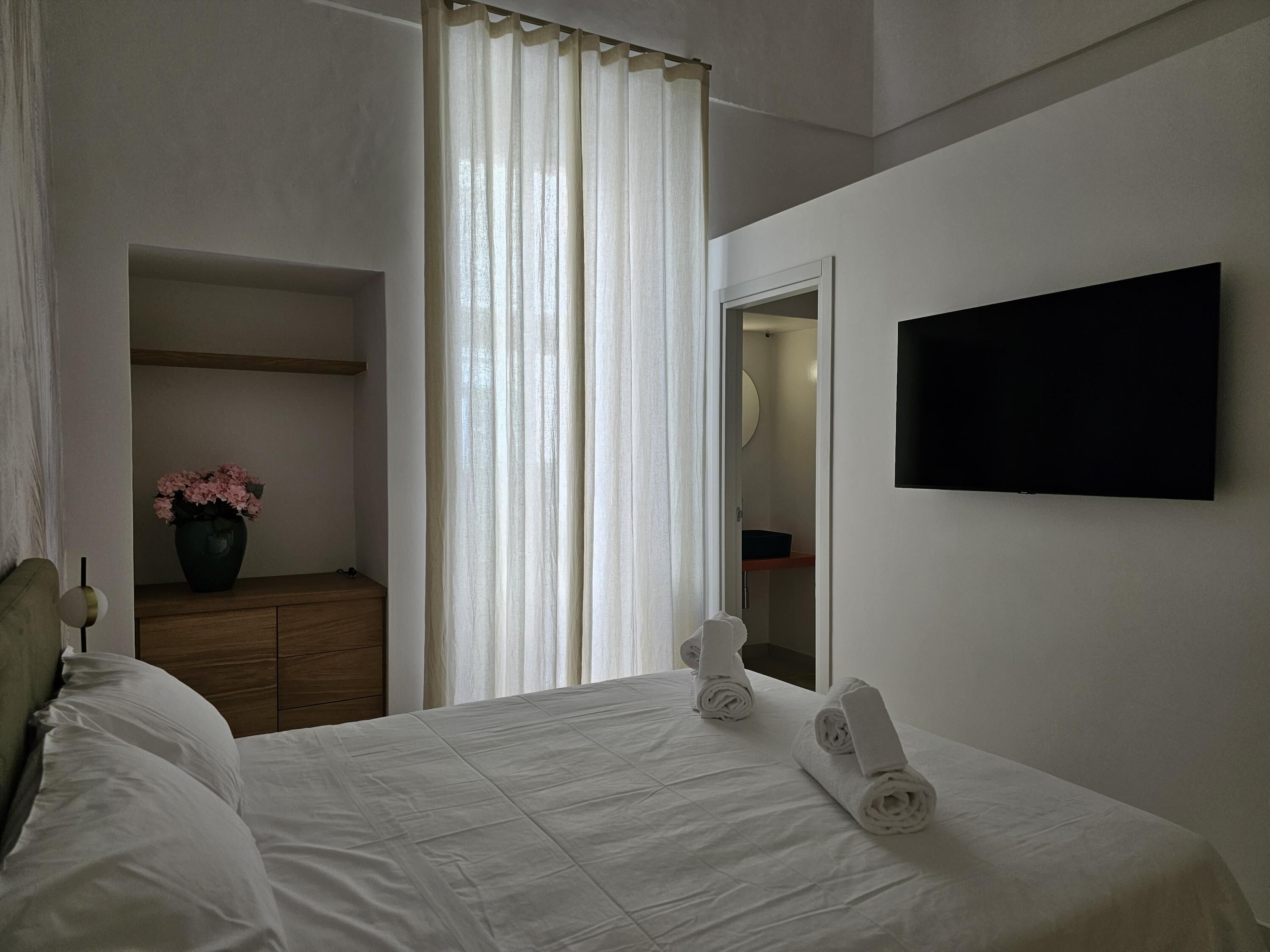 A hotel room with a bed, a dresser, a mirror, and a TV.