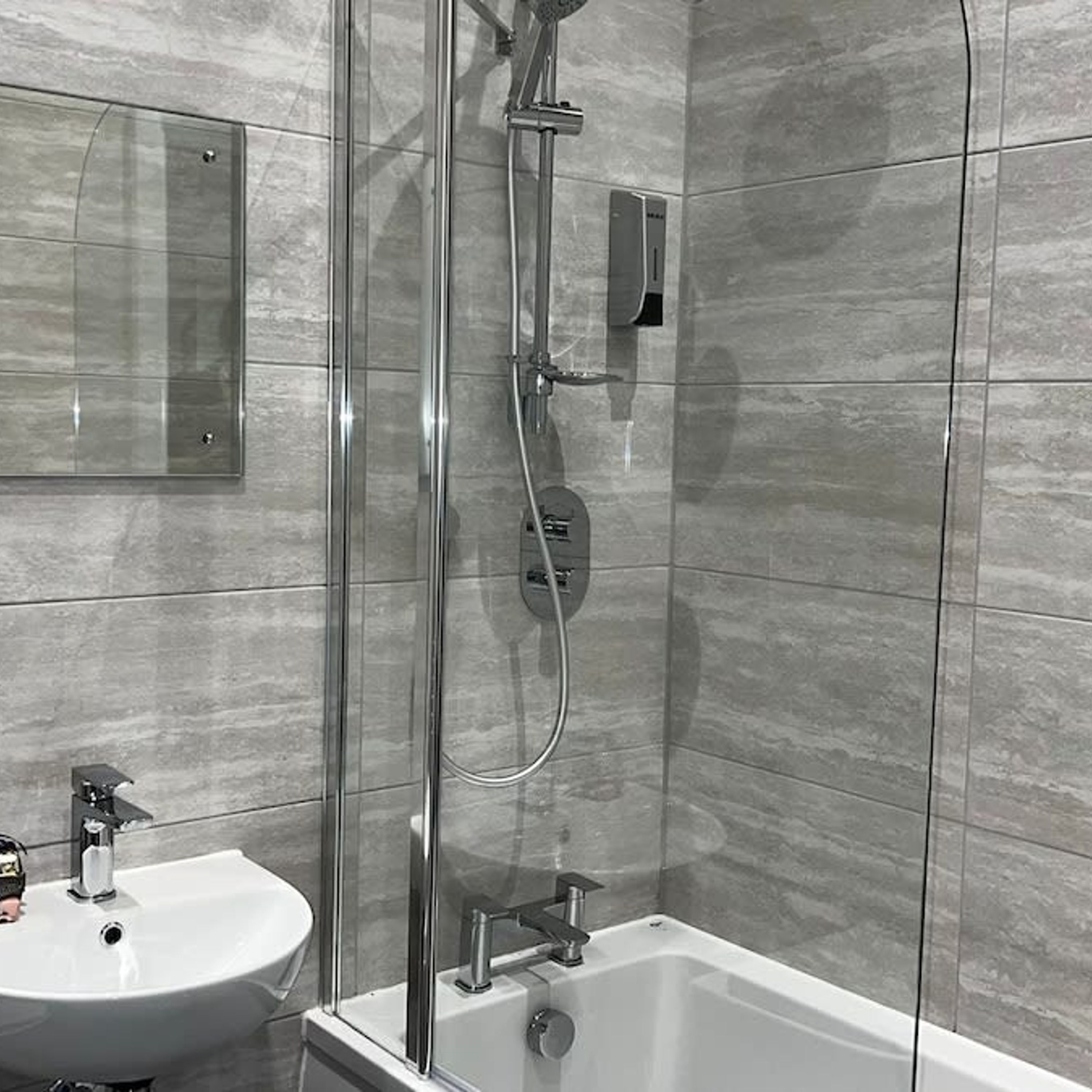 A modern bathroom with a glass-enclosed shower, a white sink, and a built-in toilet.