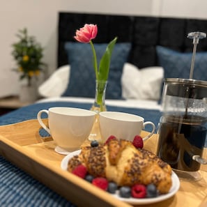 A breakfast tray with croissants, berries, and a glass of iced coffee on a wooden table. - The Gathering On The Rows - City Centre (Chester)