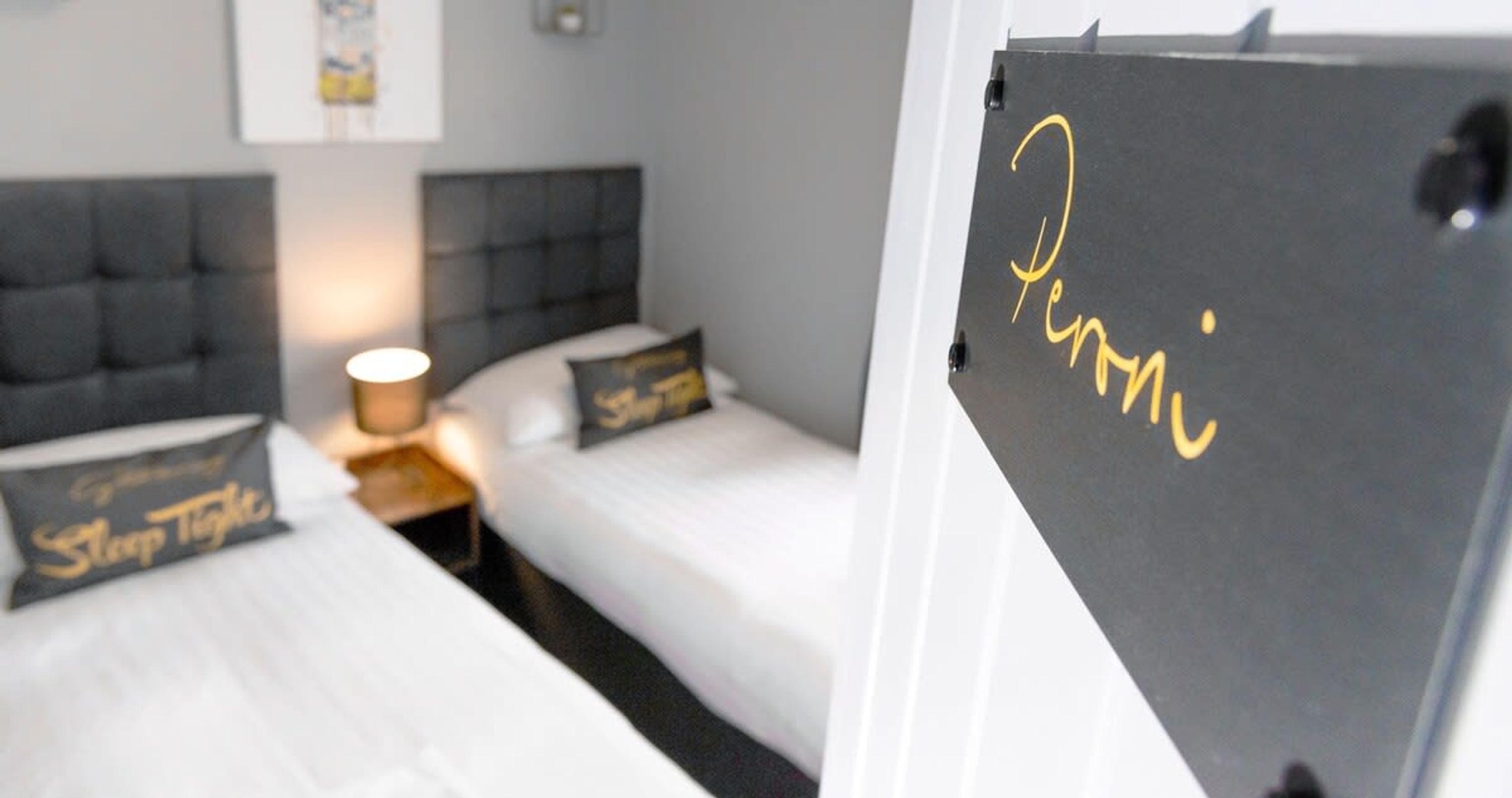 Een hotelkamer met twee bedden, een nachtkastje en een lamp.