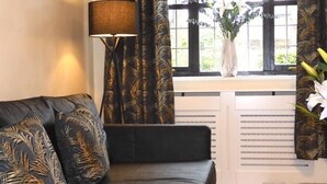 A modern living room with a black leather sofa, a wooden coffee table, and a window with curtains. - Lion House Chester - Very Near Zoo Ideal for Families (Chester)