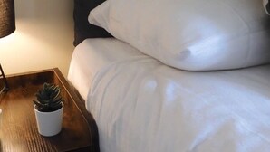 A neatly made bed with white bedding, a dark headboard, and a small potted plant on the nightstand. - Lion House Chester - Very Near Zoo Ideal for Families (Chester)
