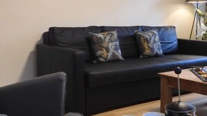 A living room with a black sofa, two pillows, a wooden coffee table with a coffee pot, two yellow mugs, and a tray. - Lion House Chester - Very Near Zoo Ideal for Families (Chester)