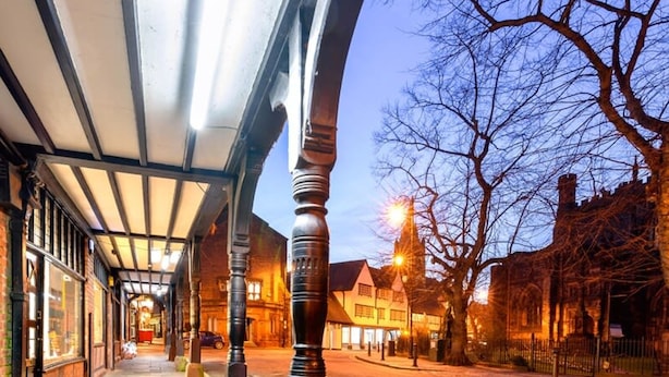 A street view with a covered walkway, stone bollards, and traditional buildings. - The Lombard House - City Centre (Chester)