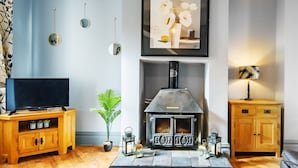 A living room with a fireplace, a television on a wooden stand, and a cabinet with drawers. - The Kings Gathering - Very Central Chester (Chester)