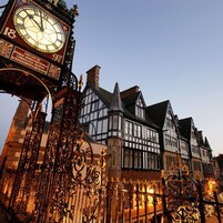 Un edificio storico con architettura in stile Tudor, caratterizzato da un'imponente torre dell'orologio e decorazioni in ferro battuto.