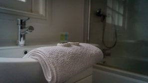 Un baño con una bañera blanca, una toalla y una cabina de ducha de vidrio.