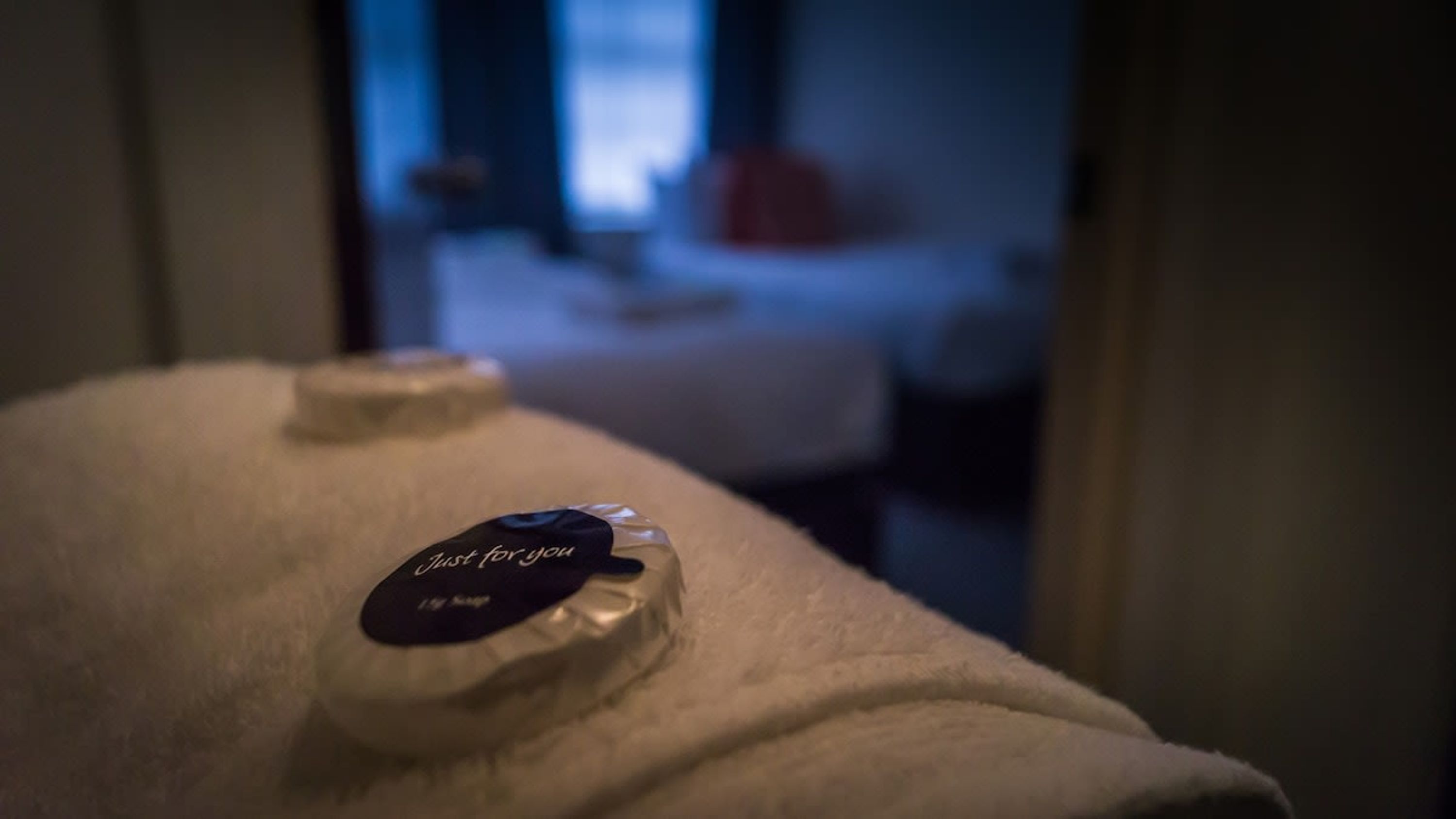 Une chambre avec un lit blanc et une bouteille de lotion étiquetée « spécialement pour vous » posée sur le lit.