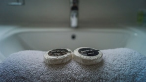 Deux savons sur une serviette blanche, dans le lavabo d’une salle de bain.