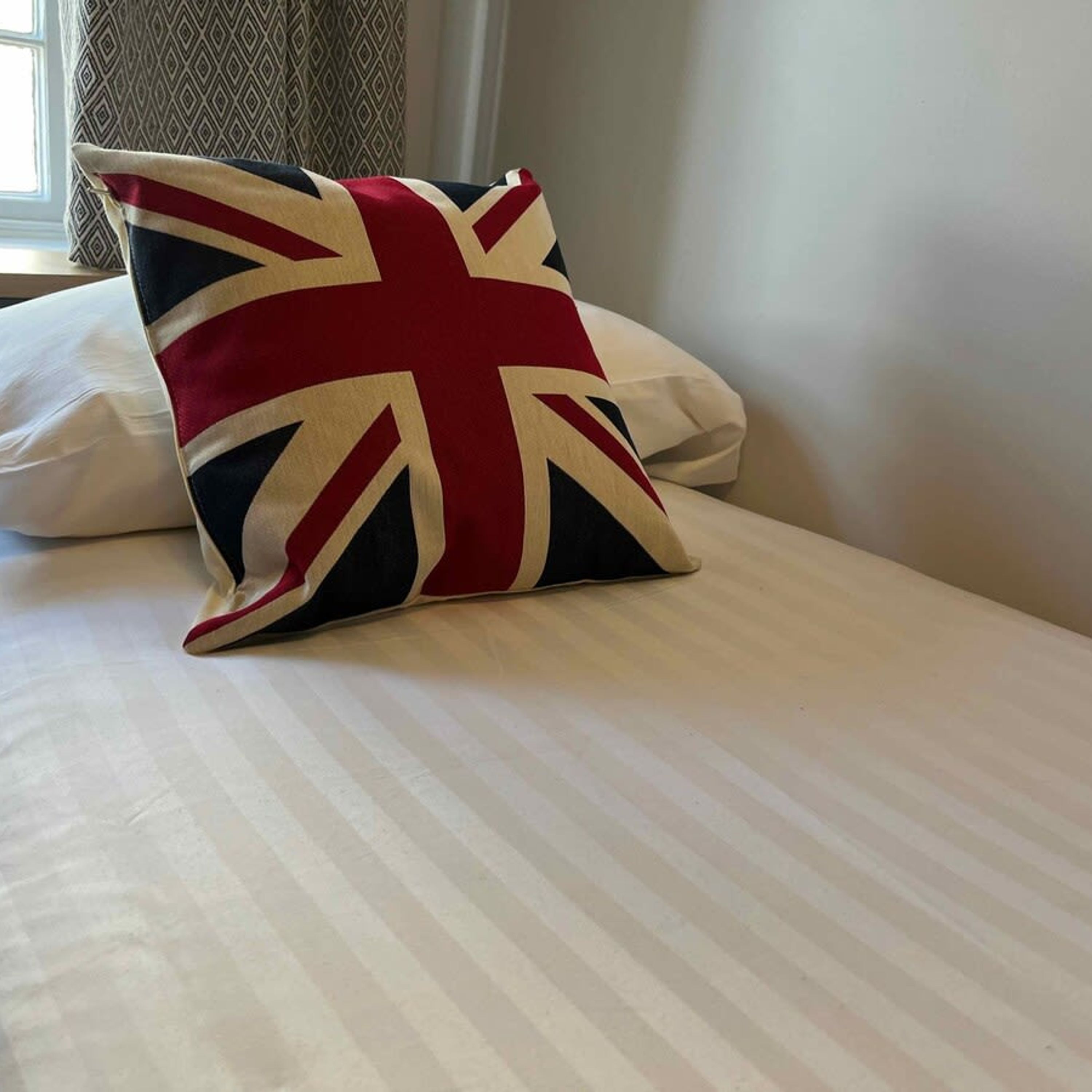 A bed with a pillow featuring a Union Jack design.