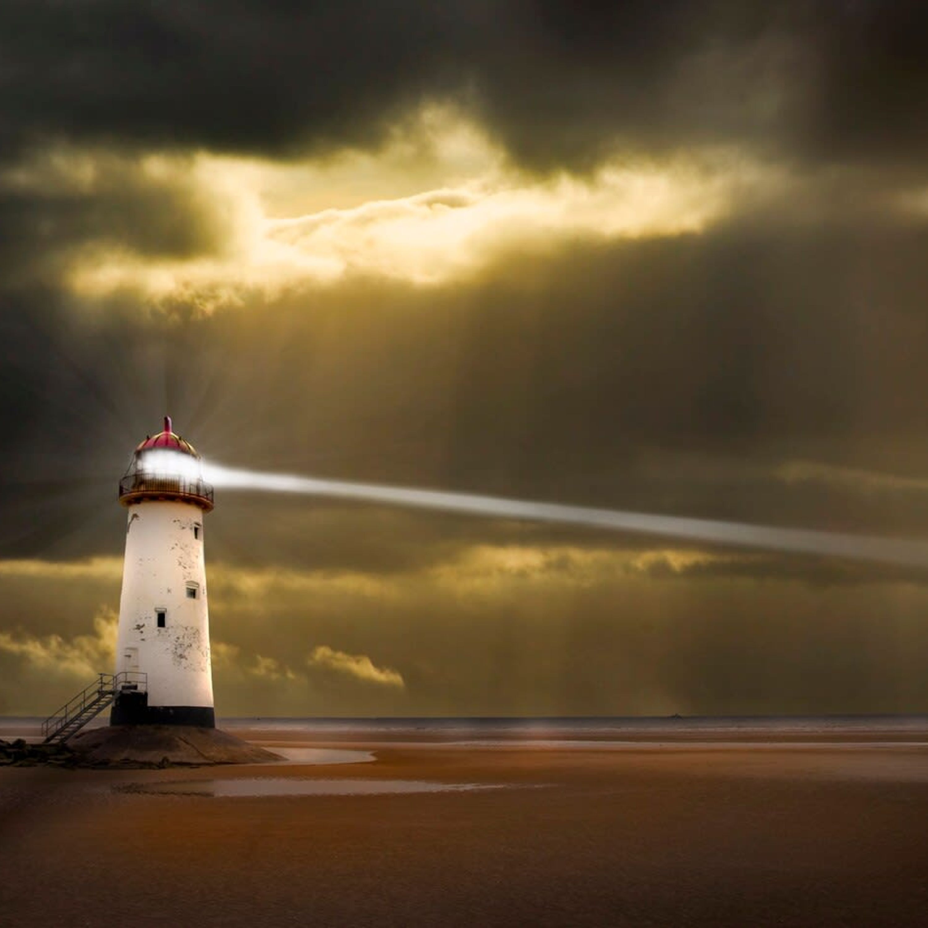 A lighthouse on a sandy beach with a stormy sky.