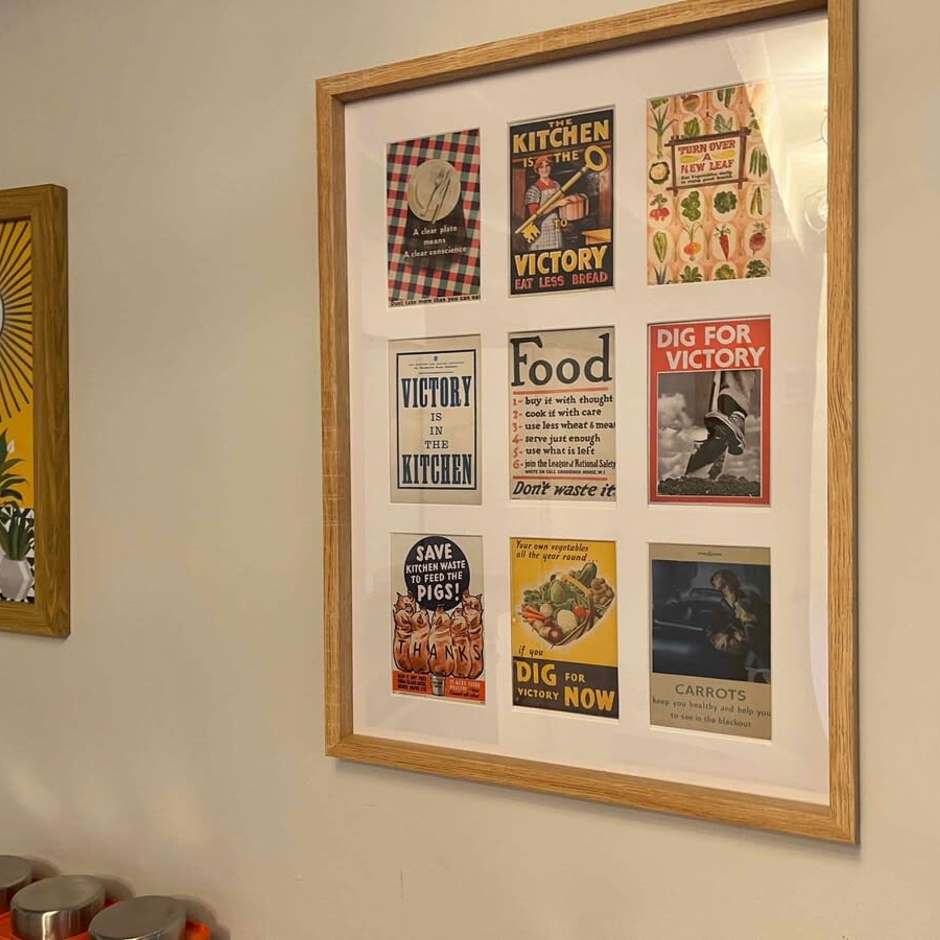 A framed collage of vintage food and kitchen posters on a wall.