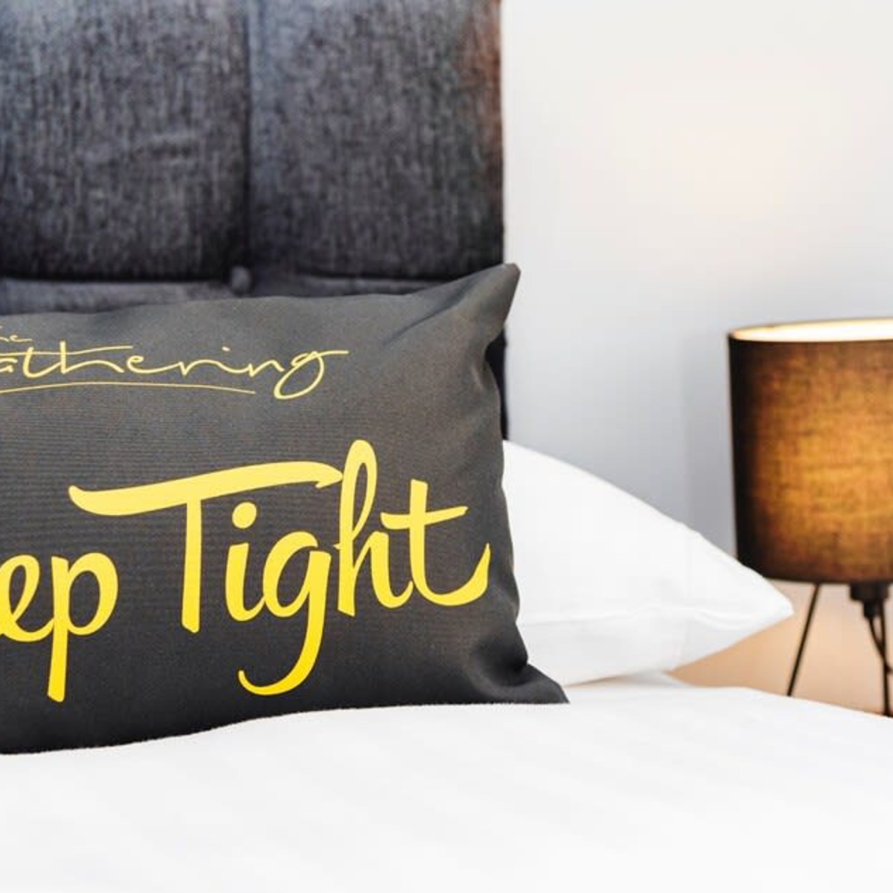 A pillow with the text "Bathing" and "keep Tight" on a bed.
