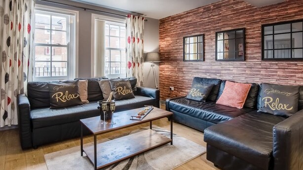 Ein modernes Wohnzimmer mit zwei Ledersofas, einem Couchtisch und einer Ziegelwand.