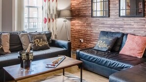 Ein modernes Wohnzimmer mit zwei Ledersofas, einem Couchtisch und einer Wand mit Backsteinverkleidung.