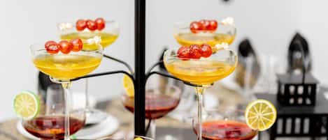 Un bar avec de nombreux verres de cocktails, décorés de cerises et de tranches d’agrumes.
