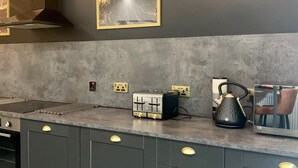 Eine moderne Küche mit grauen Schränken, einer Edelstahl-Dunstabzugshaube, einer Marmor-Spritzschutzwand und einem Toaster auf der Arbeitsfläche.