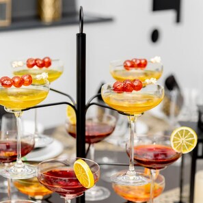 Une variété de cocktails servis dans différents types de verres, certains étant décorés de tranches d’agrumes et de fruits rouges.