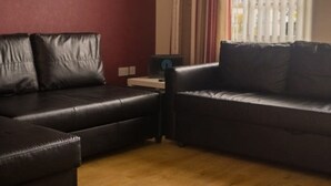 Ein Wohnzimmer mit zwei schwarzen Ledersofas, einem kleinen Tisch und einem Spiegel an der Wand.