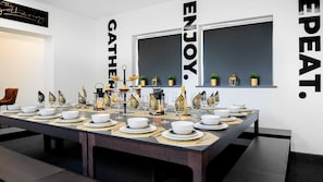 A dining table set with white plates, glasses, and cutlery, with decorative items and a bottle of champagne. - The Leeds Gathering - Hot Tub - EV Charging (Leeds)