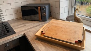 A kitchen with a microwave, a cutting board, and a decorative item near a window. - The Bridgewater Studio The Gathering Sale (Sale)
