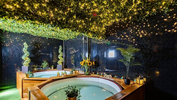 A spa area with a wooden bench, a hot tub, and a ceiling covered with greenery and lights. - The Tudor Gathering Chester - City Centre (Chester)