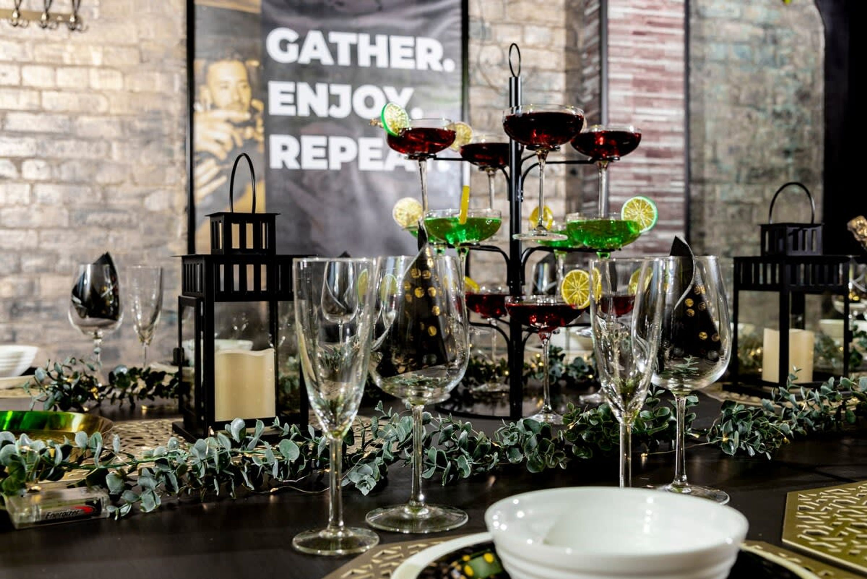 Una mesa servida con copas de vino, un soporte decorativo para bebidas y un cartel de fondo.