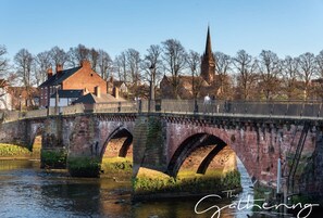 A stone bridge over a river with a church in the background.