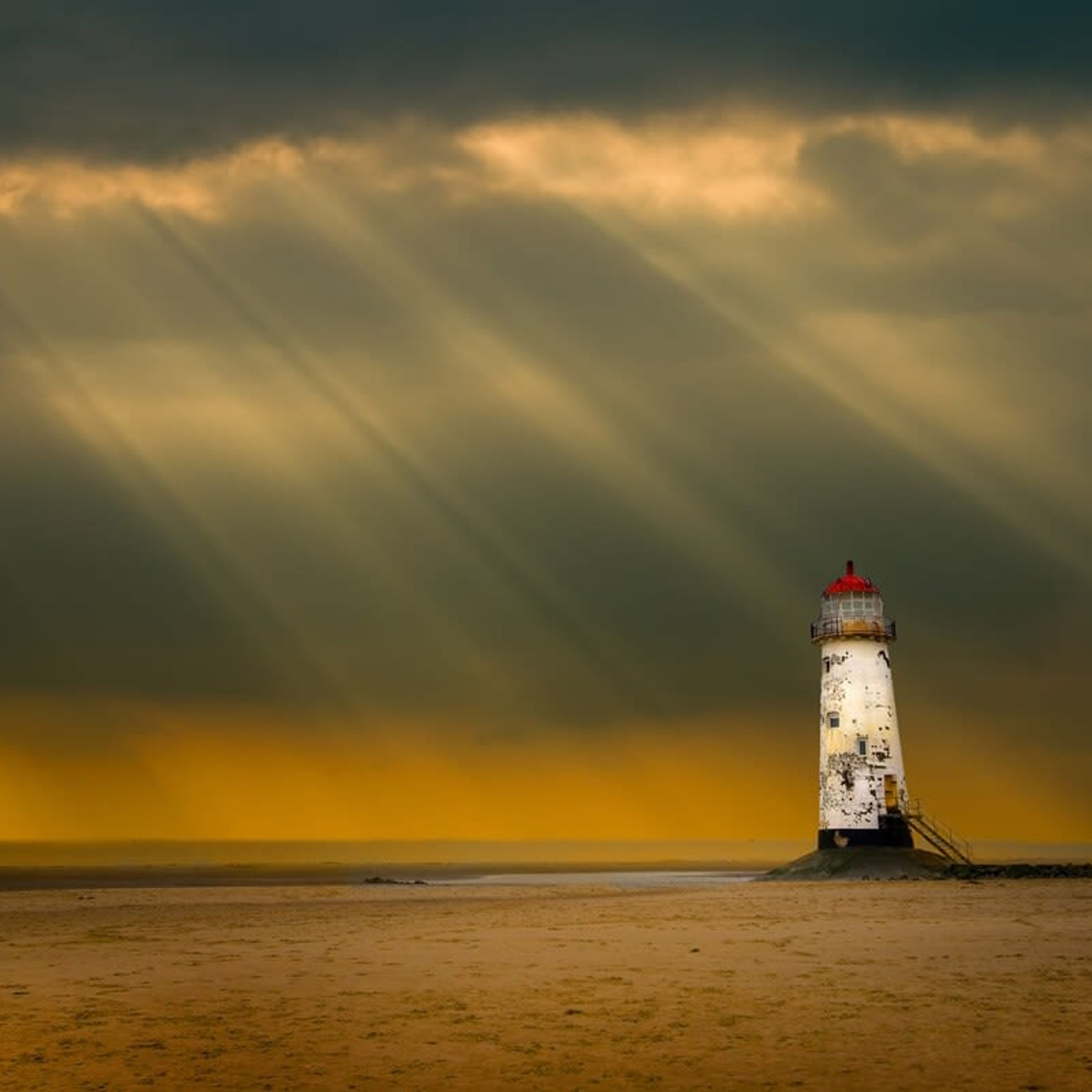 Un faro en una playa arenosa bajo un cielo dramático.