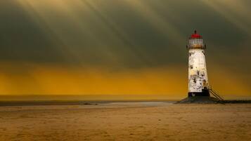 Un faro en una playa arenosa bajo un cielo dramático.