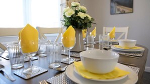 A dining table set with clear glassware, white bowls, and yellow napkins. - The Flintshire - Flint (Flint)