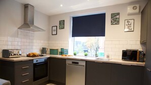 A modern kitchen with a dishwasher, oven, and a window with a view of the outdoors. - The Gathering Sale - Sleeps Up To 22 (Sale)