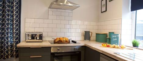 A modern kitchen with a built-in oven, a toaster, and a variety of fruits and vegetables on the counter.