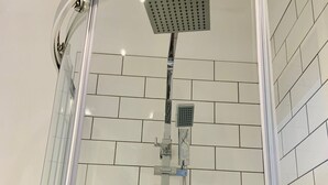 A shower with a glass enclosure, a handheld showerhead, and a wall-mounted control panel. - The Islington Studio The Gathering Sale (Sale)