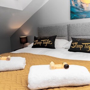 Relax in a serene space with a neatly made bed, a wooden headboard, and a beautiful wave painting.