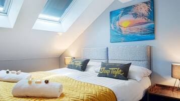 A bedroom with a bed, pillows, a painting, and a skylight.