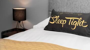 A neatly made bed with a pillow labeled "Sleep Tight" and two bottles on the bed.