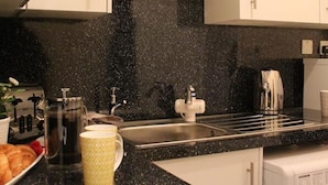 A kitchen with white cabinets, a black countertop, and a coffee maker. - The Eisteddfod - Berwyn House Central Wrexham (Wrexham)